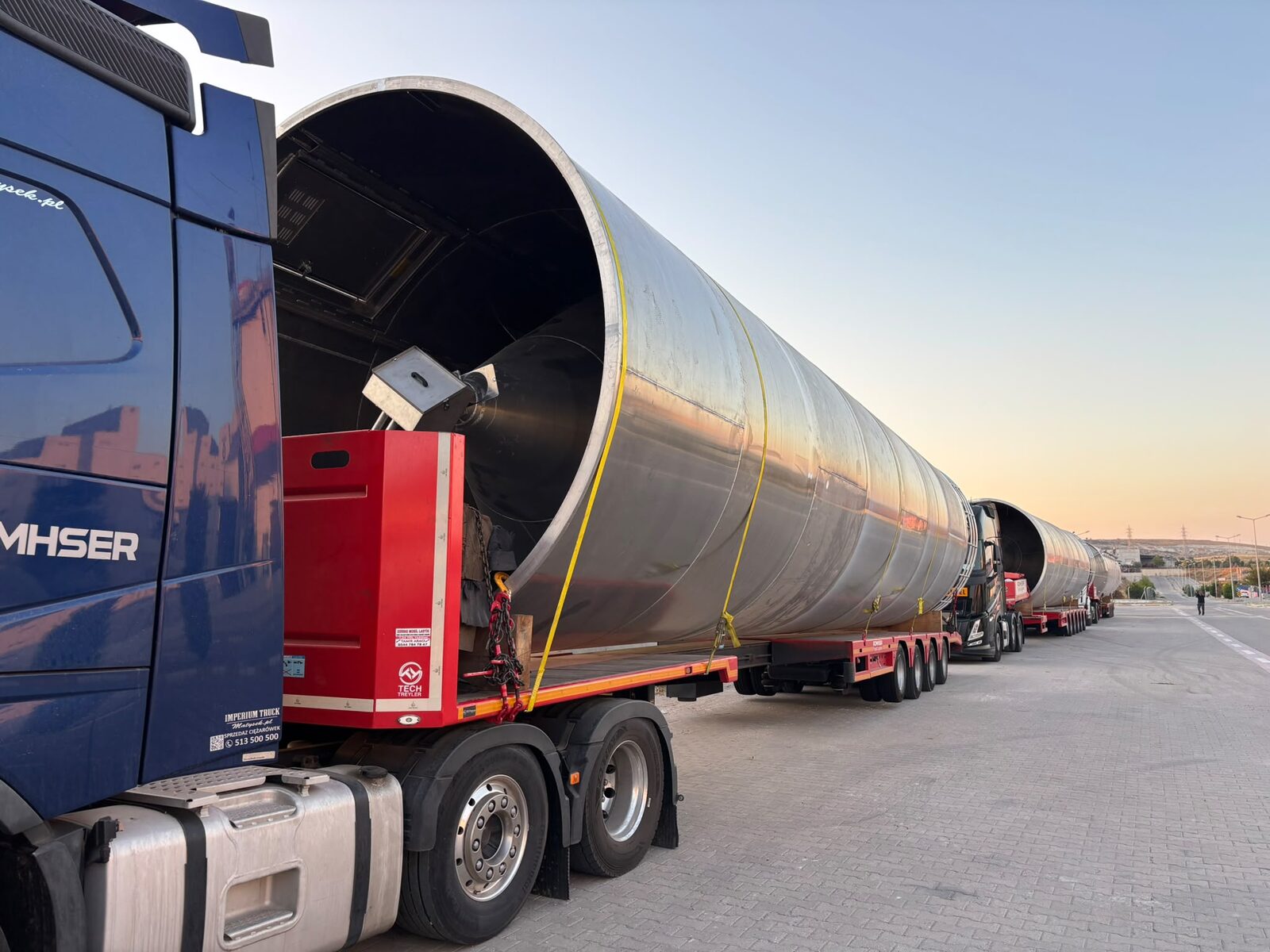 A giant stainless raw-material storage silo being transported to the production area